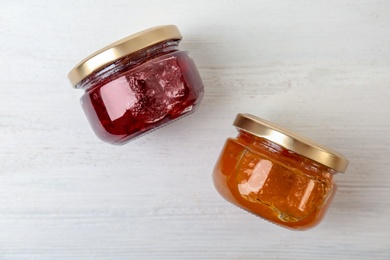 Photo of Two jars with tasty sweet jam on white wooden table