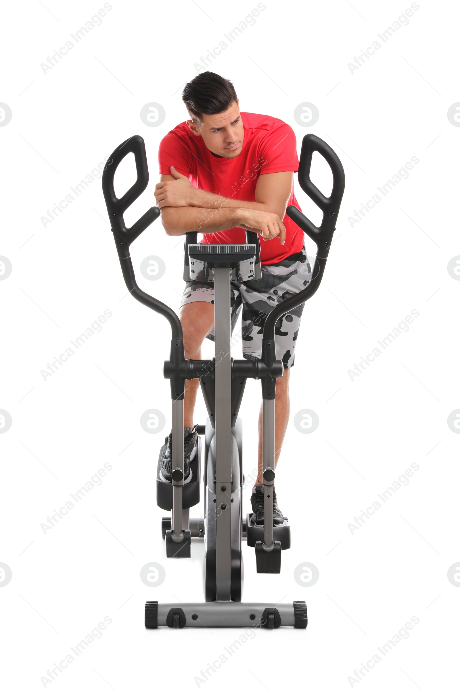 Photo of Tired man after training on modern elliptical machine against white background