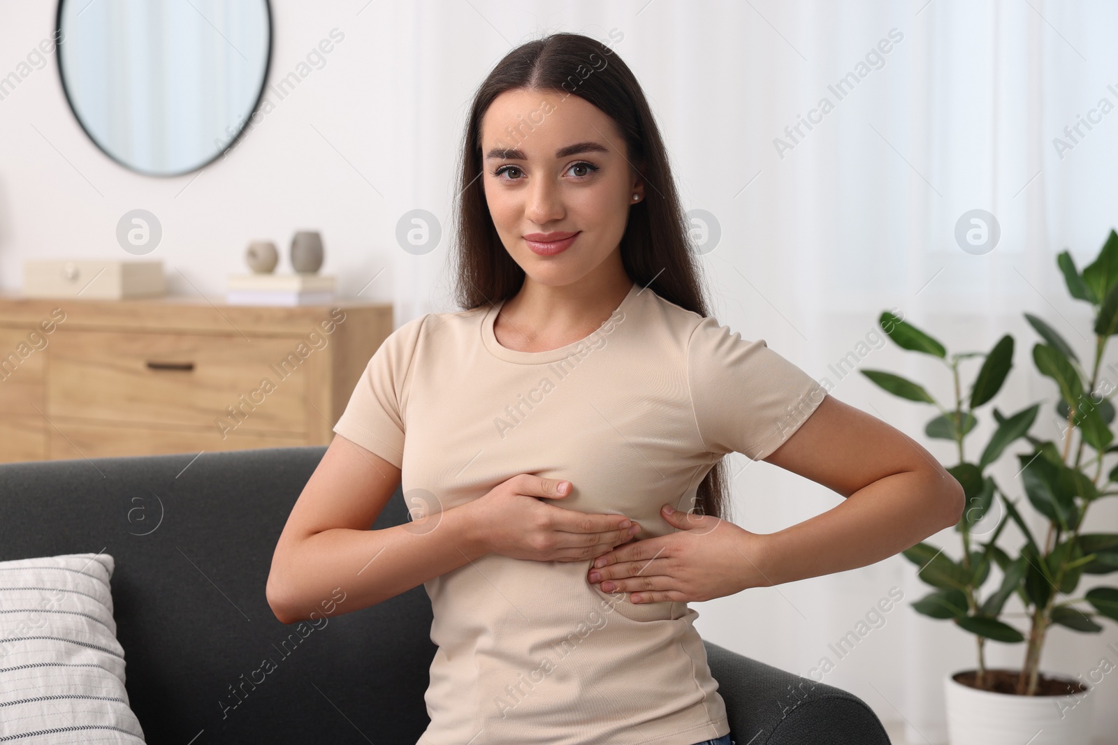 Photo of Beautiful young woman doing breast self-examination at home