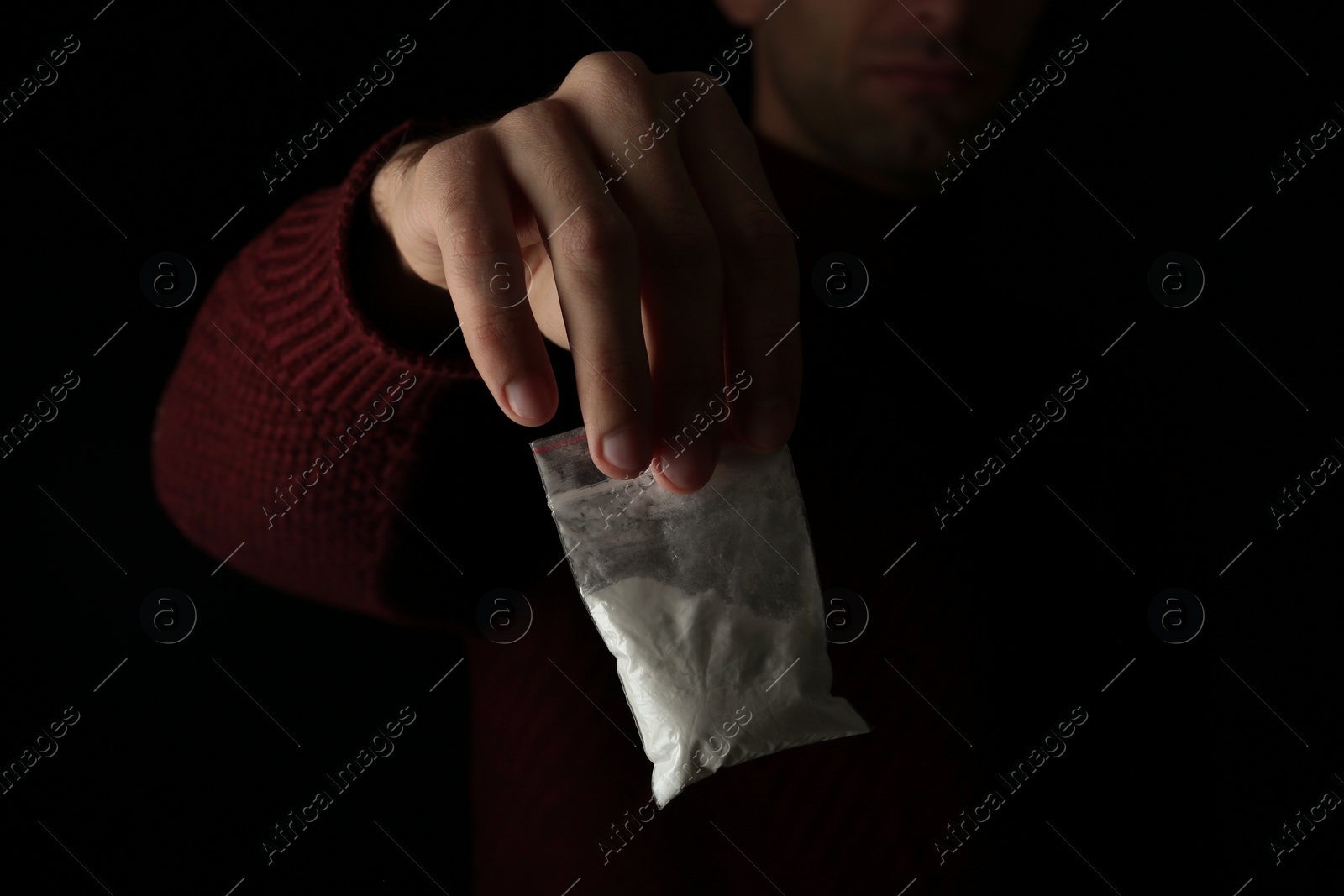 Photo of Drug dealer holding bag with cocaine on black background, closeup. Space for text