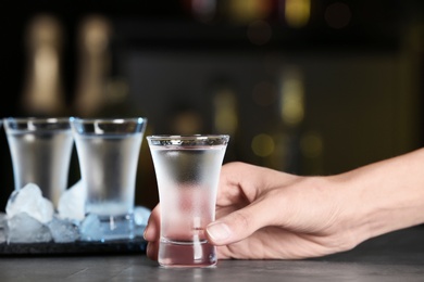 Woman with shot of vodka at table in bar, closeup