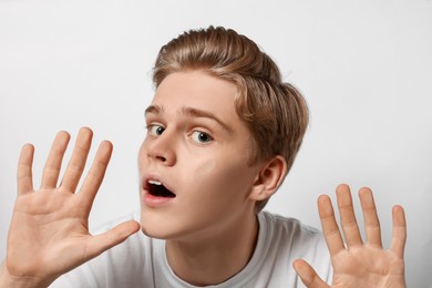 Photo of Shocked teenage boy stuck to transparent screen