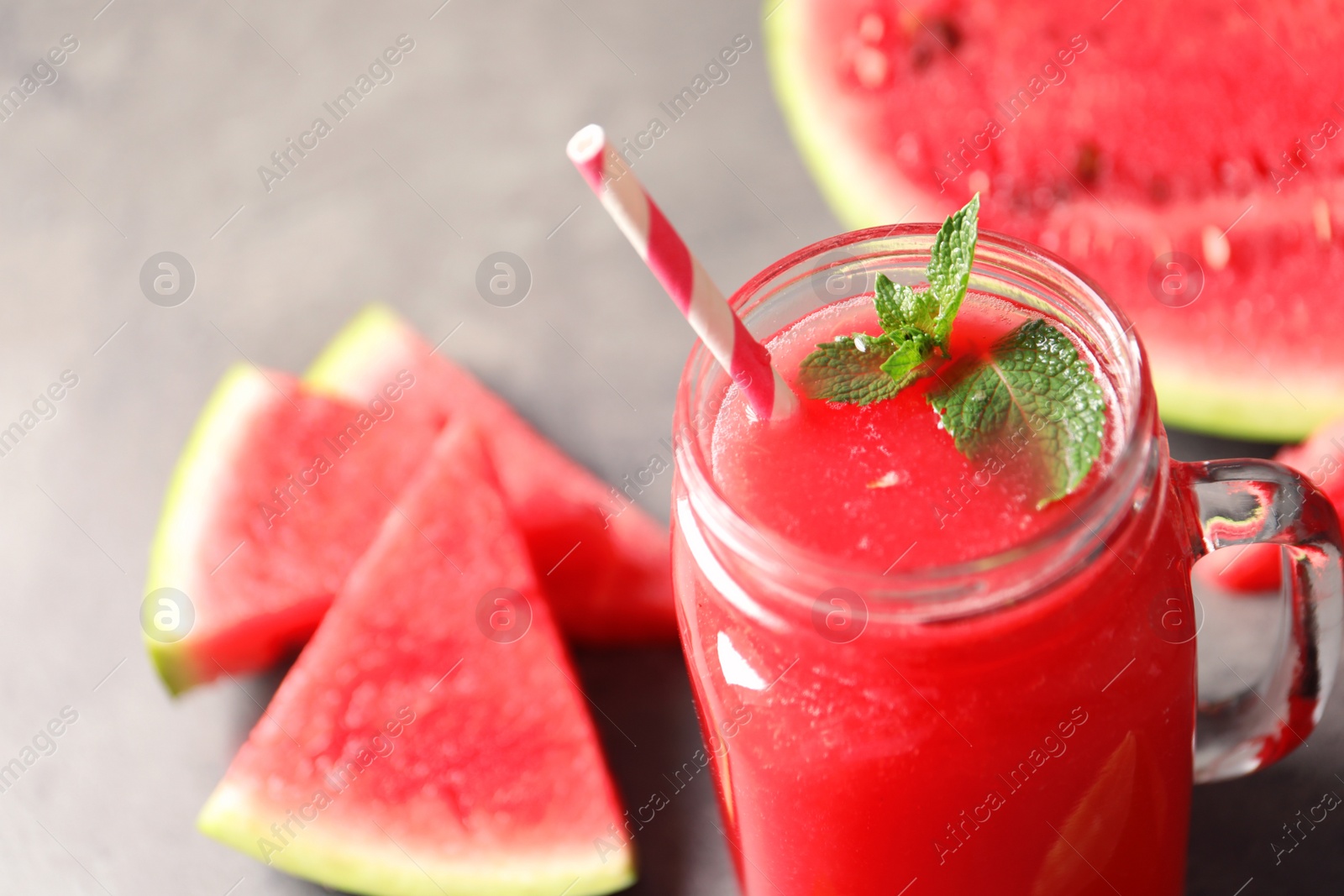 Photo of Summer watermelon drink with mint in mason jar and sliced fruit on table