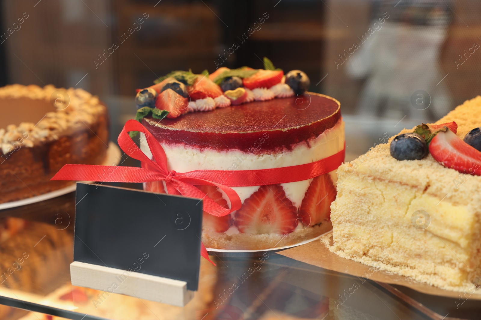 Photo of Delicious cake with strawberries on counter in bakery shop, closeup