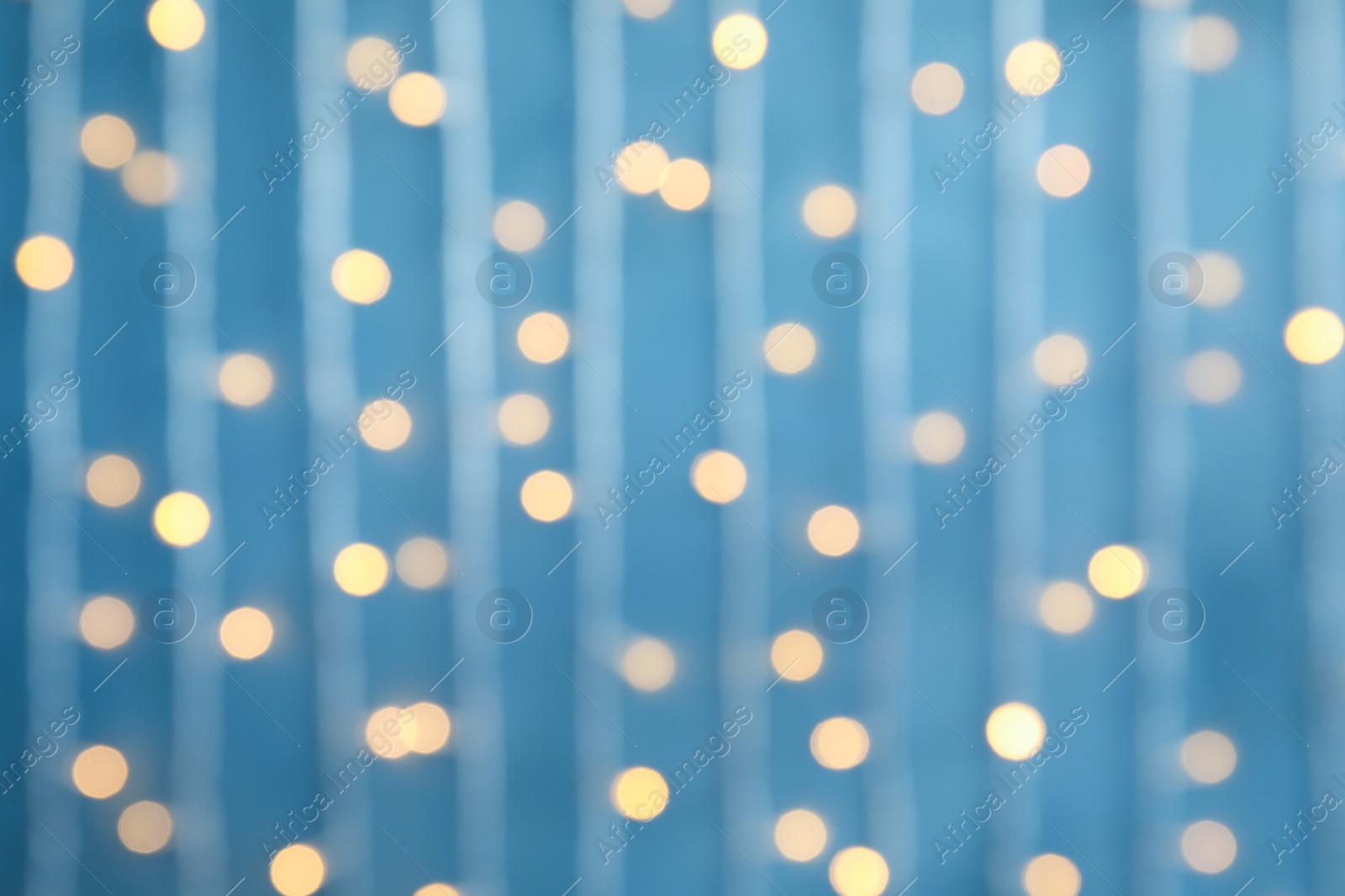 Photo of Blurred view of Christmas lights on color background