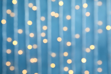 Blurred view of Christmas lights on color background