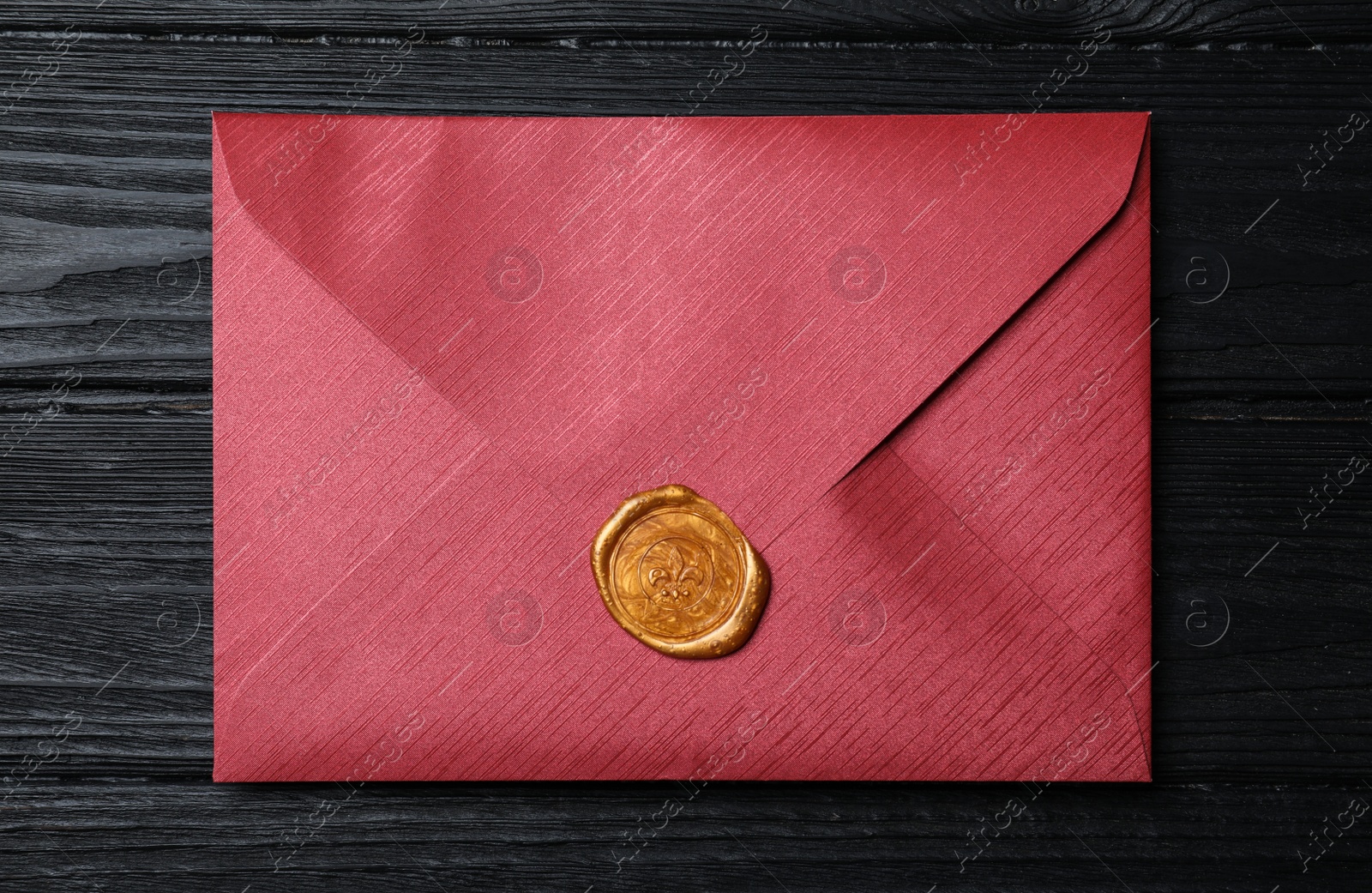 Photo of Envelope with wax seal on black wooden background, top view