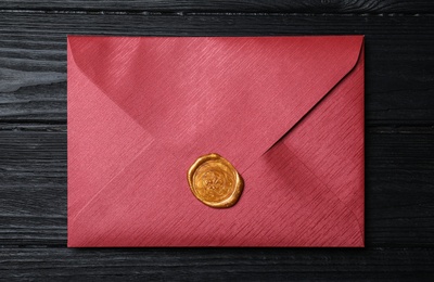 Photo of Envelope with wax seal on black wooden background, top view