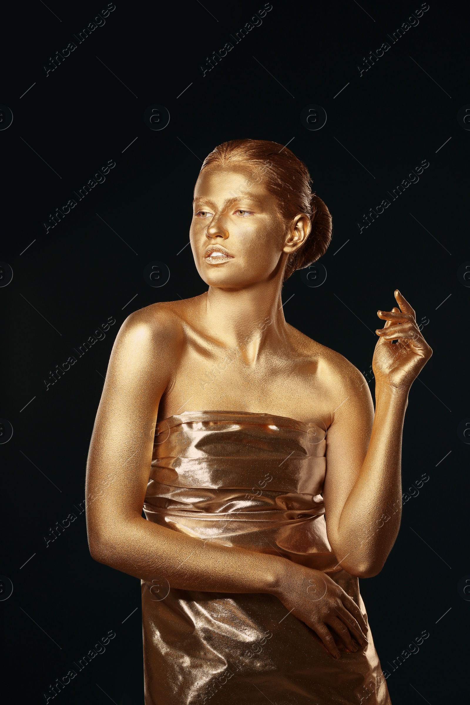 Photo of Portrait of beautiful lady with gold paint on skin against black background