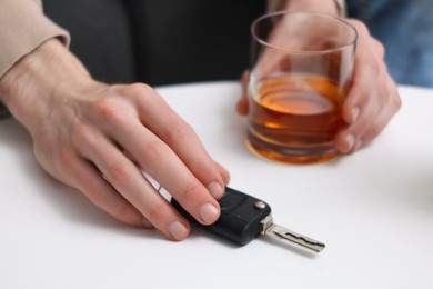 Photo of Man with glass of alcoholic drink and car keys at table, closeup. Don't drink and drive concept