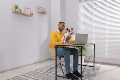 Photo of Young man with Jack Russell Terrier working at desk in home office