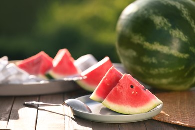 Slices of tasty ripe watermelon on wooden table outdoors