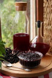 Photo of Elderberry jam and drink with Sambucus berries on table near window