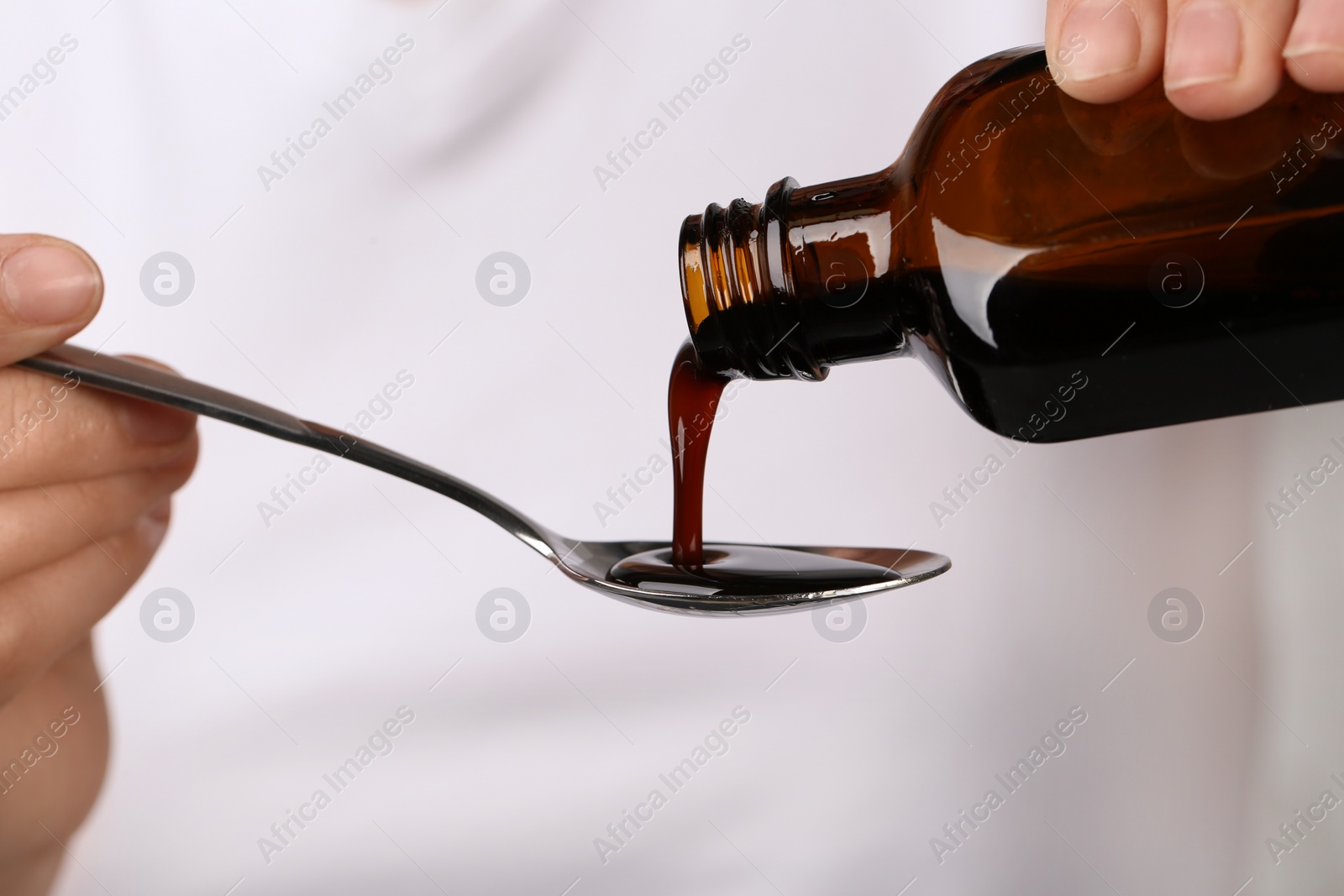 Photo of Woman pouring cough syrup into spoon, closeup