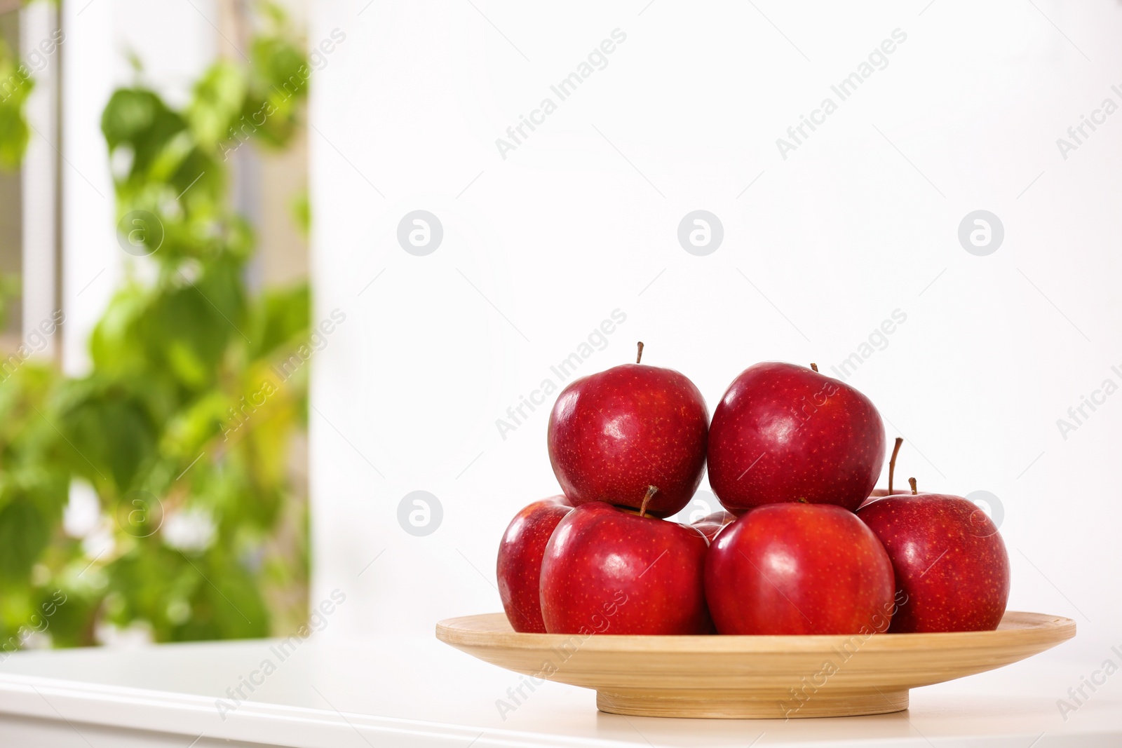 Photo of Plate with sweet red apples on commode in room, space for text