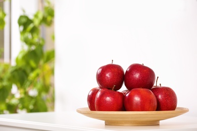 Plate with sweet red apples on commode in room, space for text