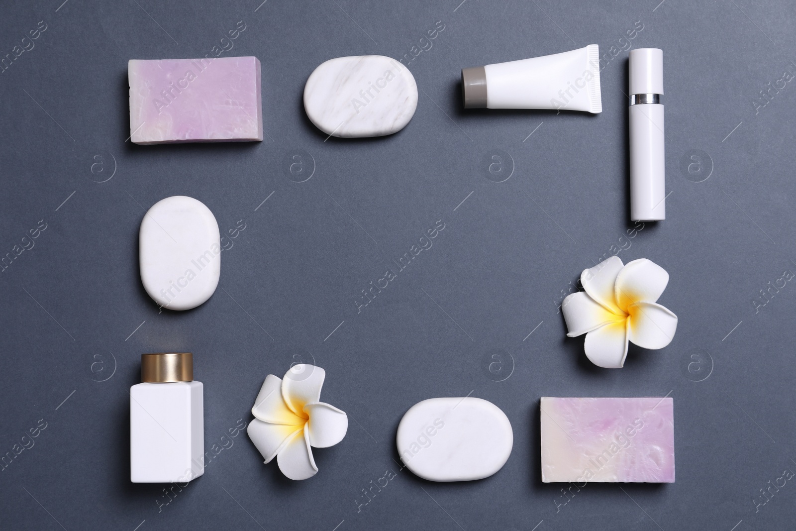 Photo of Frame of cosmetic products, spa stones and flowers on grey background. Space for text