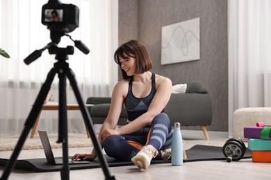 Photo of Happy sports blogger recording fitness lesson with camera at home