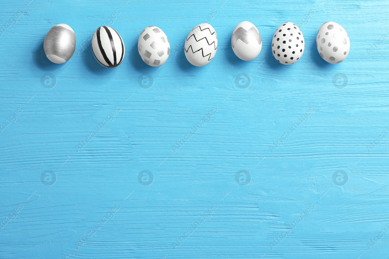 Photo of Painted Easter eggs on wooden background, flat lay with space for text