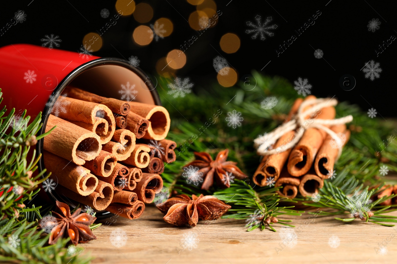 Image of Cinnamon in red mug and anise surrounded by fir tree branches on wooden table, closeup