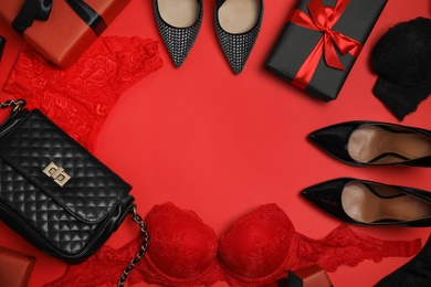 Gift boxes, women's underwear, shoes and accessories on red background, flat lay. Space for text