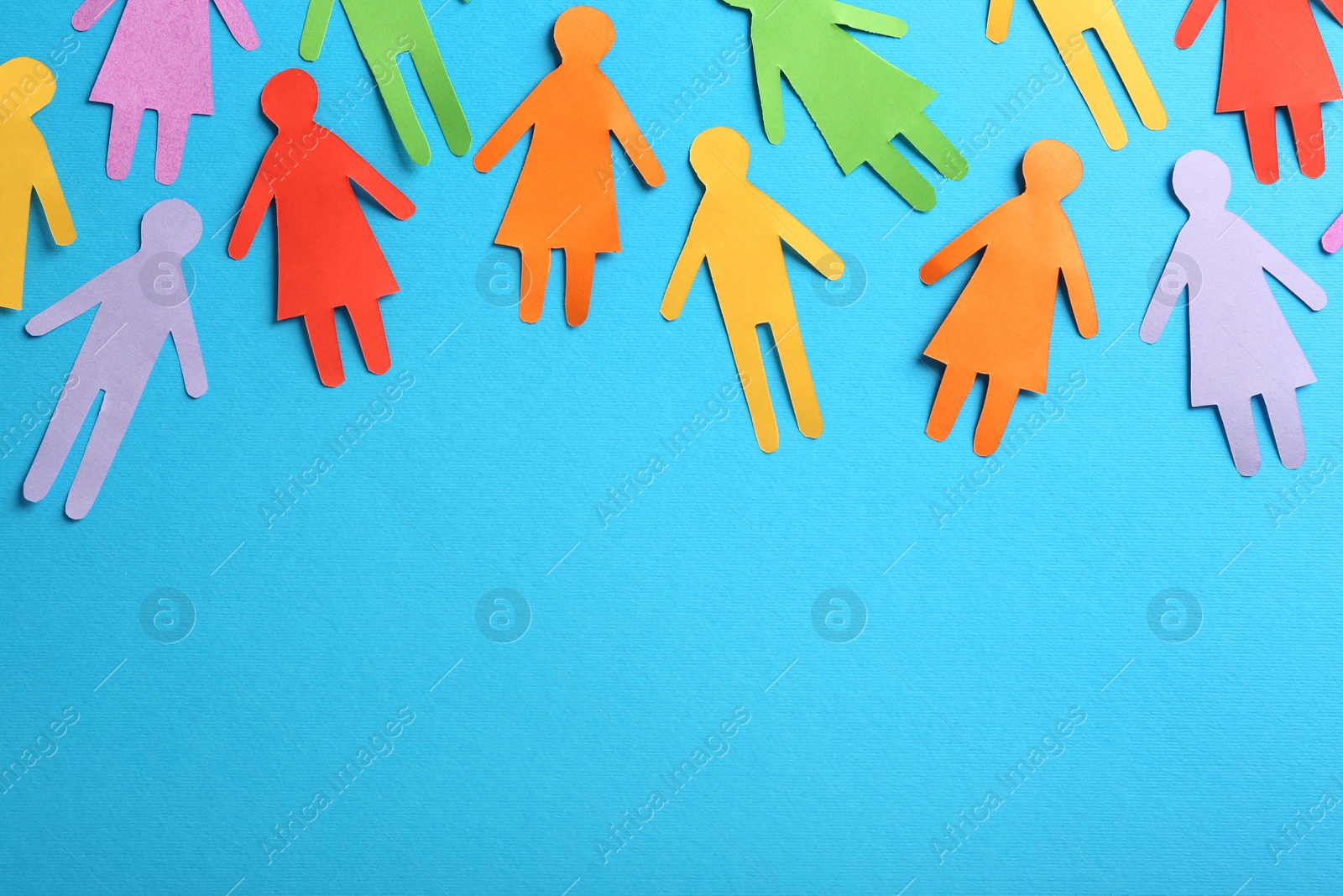 Photo of Many different paper human figures on light blue background, flat lay with space for text. Diversity and inclusion concept