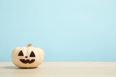 Photo of Pumpkin with scary face on light blue background, space for text. Halloween decor