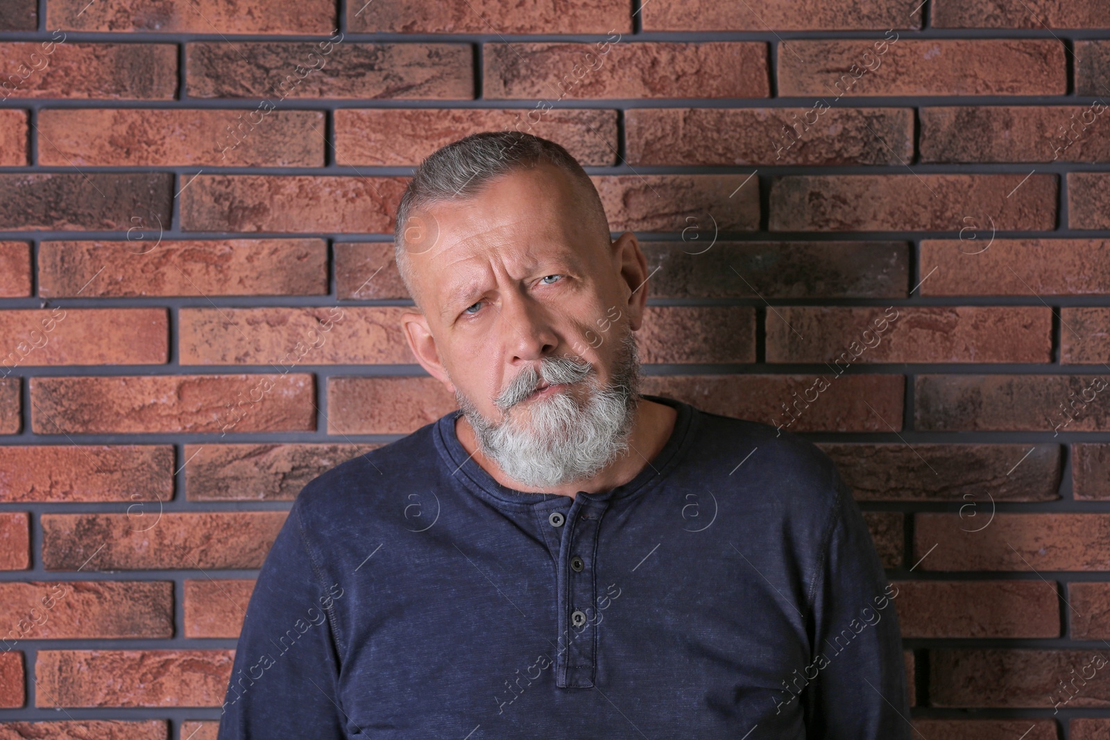 Photo of Senior man in state of depression near brick wall