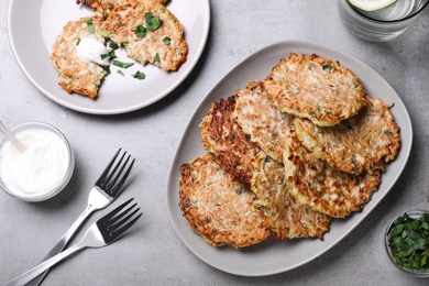Photo of Delicious zucchini fritters served on grey table, flat lay