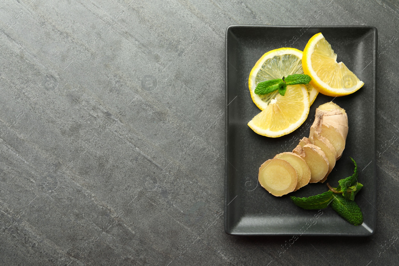 Photo of Fresh lemon, ginger and mint on grey table, top view. Space for text