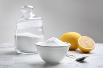 Photo of Baking soda and cut lemons on white marble table