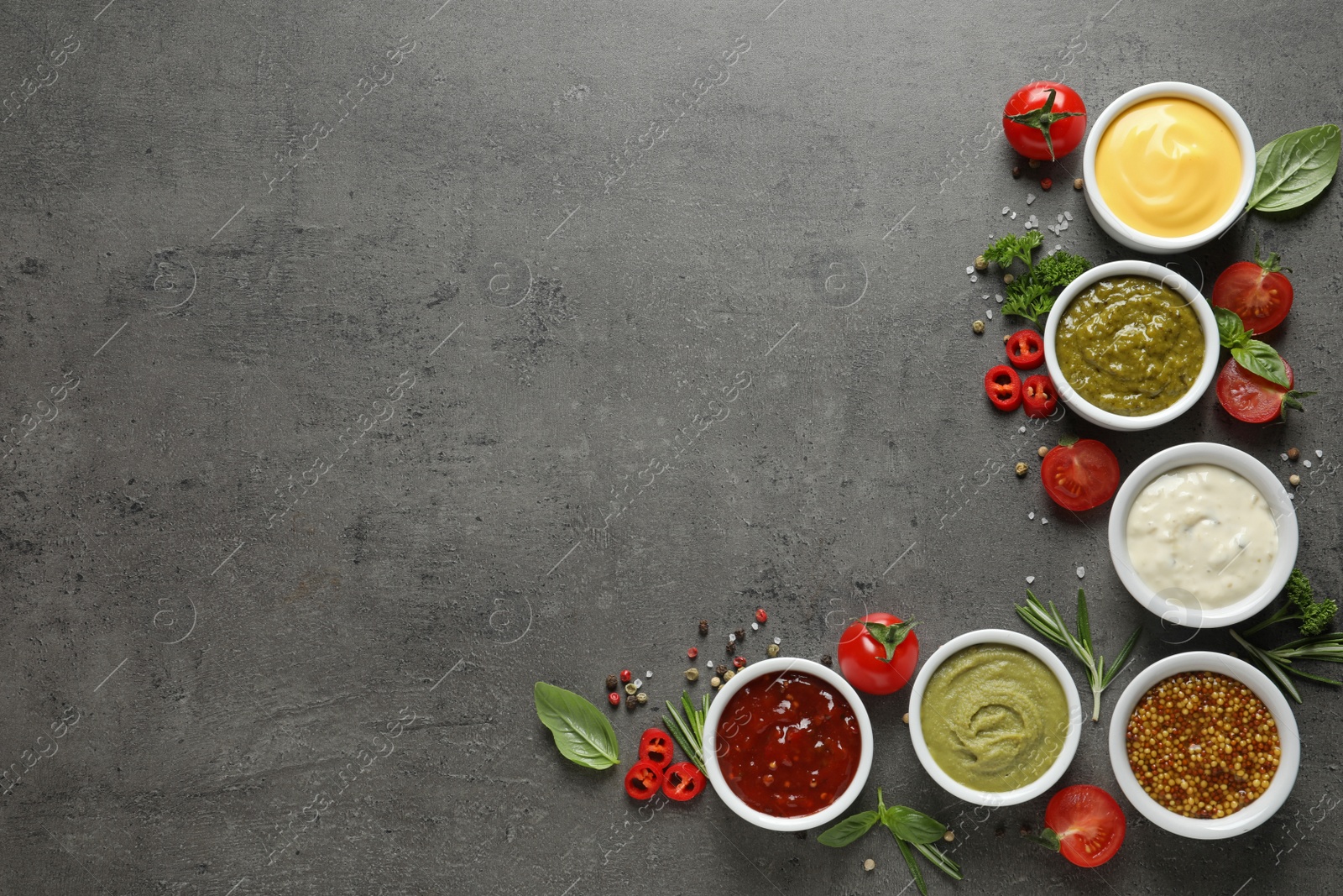 Photo of Bowls with different sauces and ingredients on gray background, flat lay. Space for text