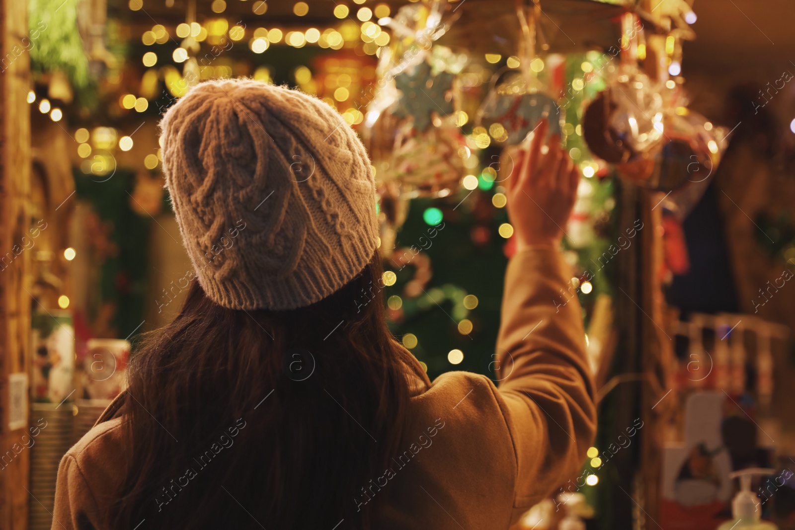 Photo of Young woman spending time at Christmas fair, back view