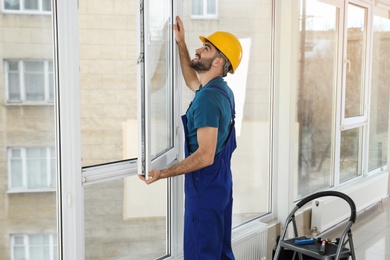 Photo of Construction worker installing plastic window in house