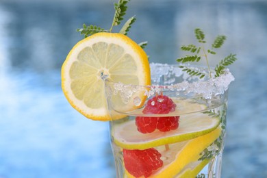 Delicious refreshing lemonade with raspberries against blurred background, closeup