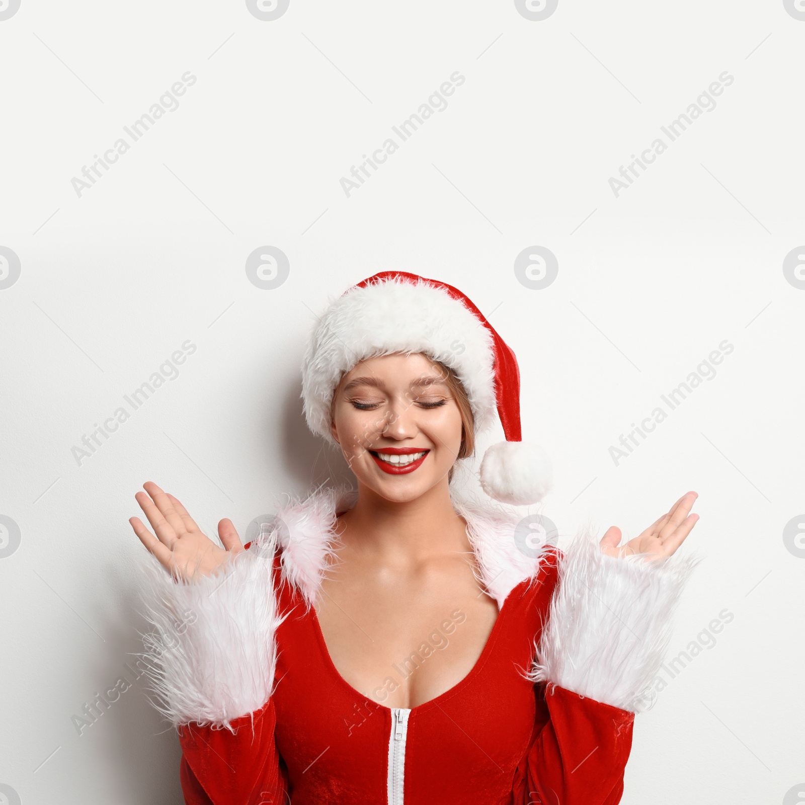 Photo of Beautiful Santa girl on light background. Christmas eve