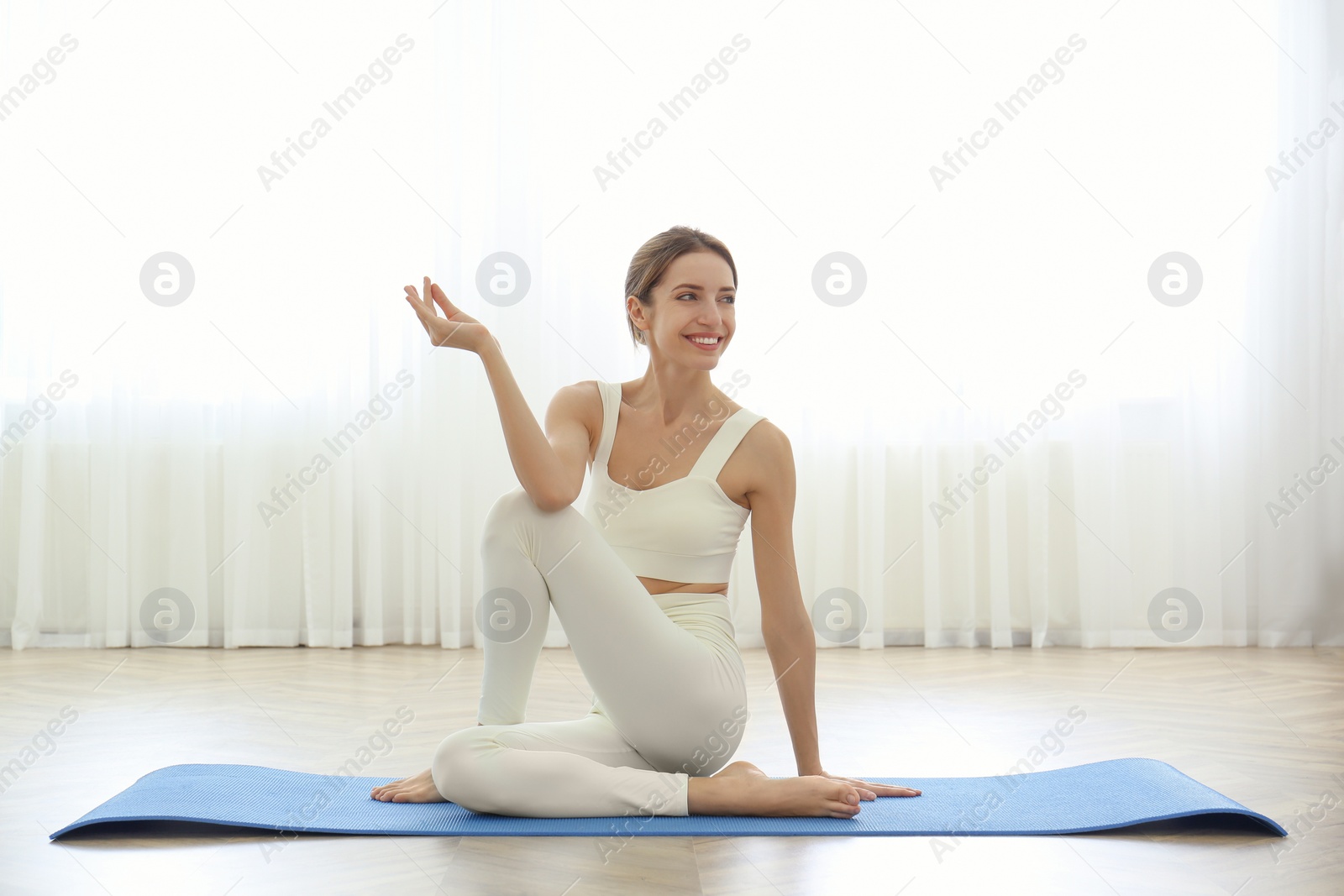 Photo of Young woman practicing half lord of fishes asana in yoga studio. Ardha Matsyendrasana pose