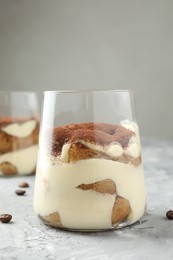 Photo of Delicious tiramisu in glass on grey textured table, closeup