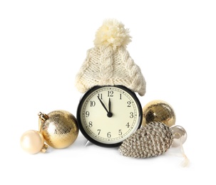 Photo of Alarm clock with hat and festive decor on white background. New Year countdown