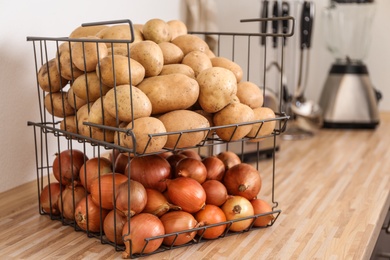 Photo of Container with potatoes and onions on wooden kitchen counter. Orderly storage