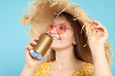 Beautiful happy woman drinking from beverage can on light blue background