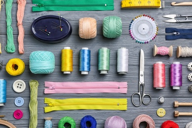 Flat lay composition with sewing threads and accessories on wooden background