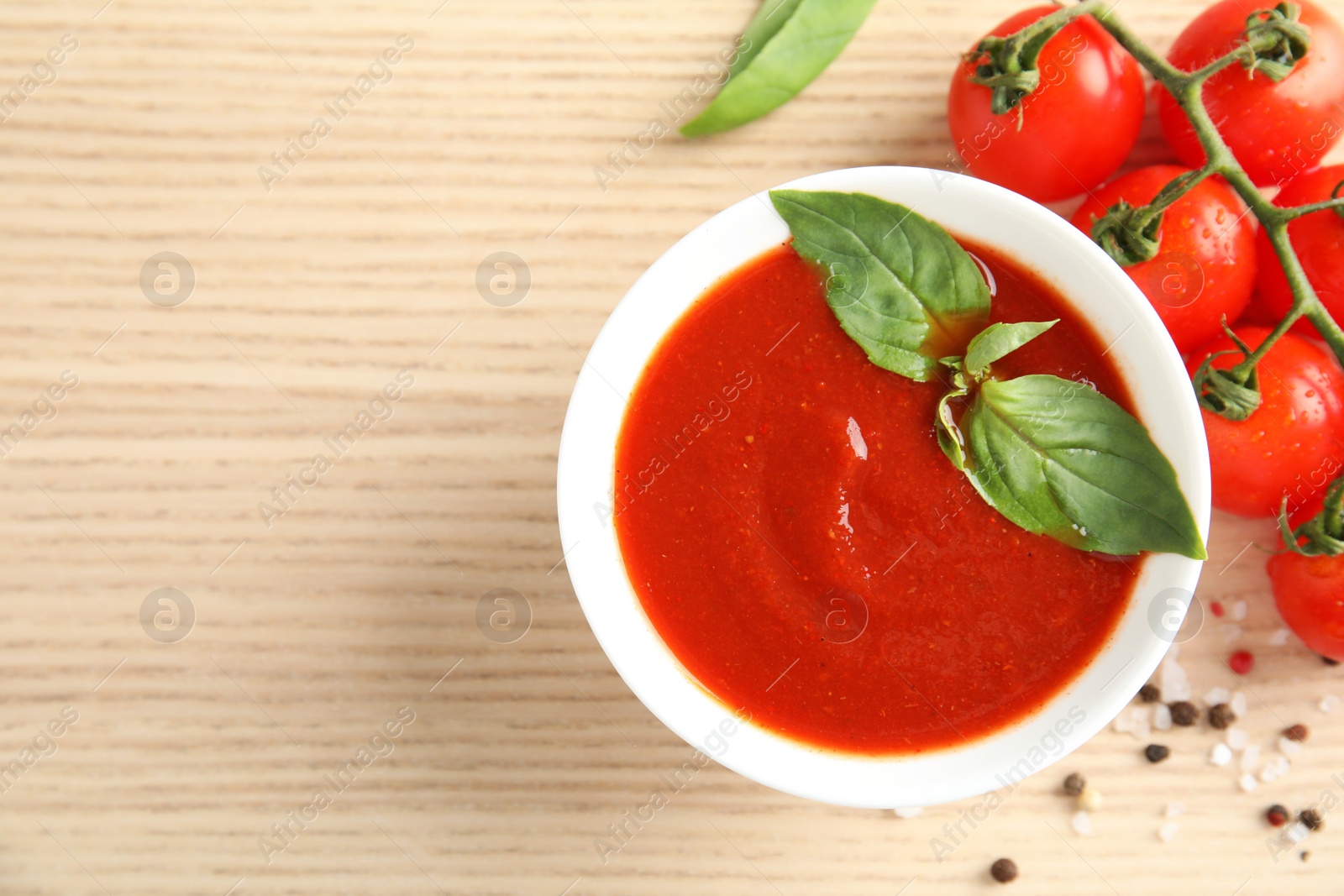 Photo of Bowl of tasty tomato sauce with basil on wooden table, flat lay. Space for text