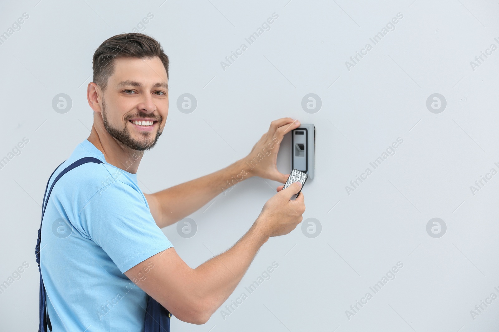 Photo of Male technician programming alarm system indoors