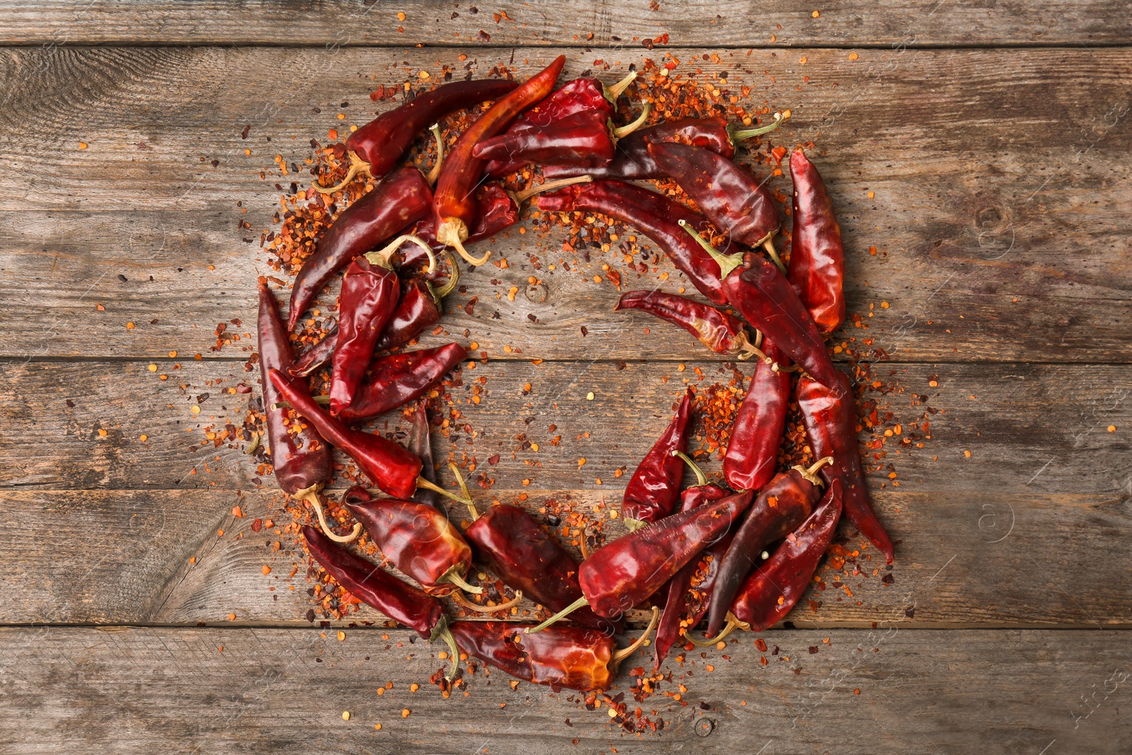 Photo of Dry chili peppers and powder on wooden background