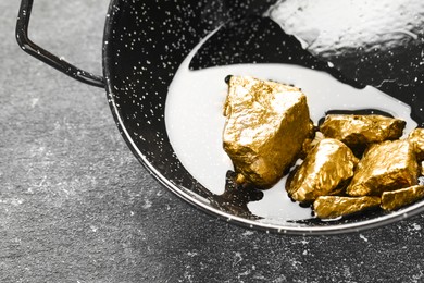 Wok with gold nuggets on grey table, closeup