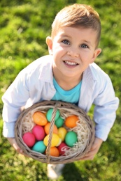 Photo of Cute little boy with basket of Easter eggs in park