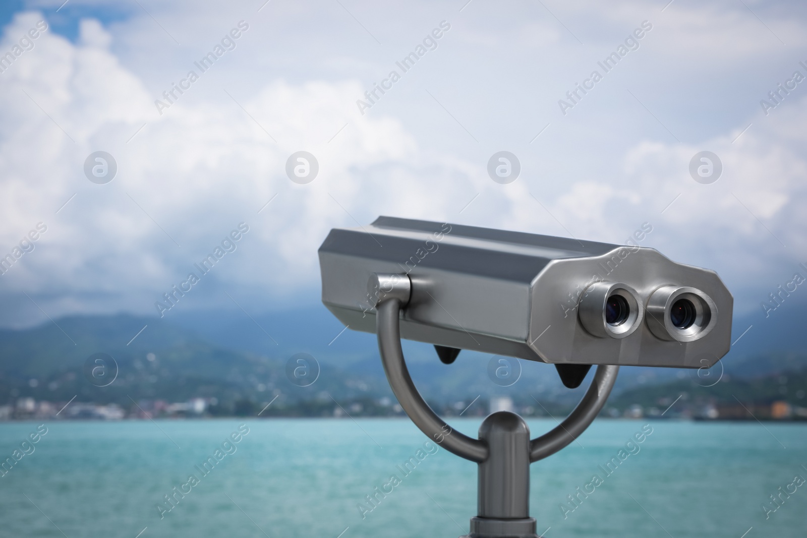 Photo of Metal tower viewer installed near sea, space for text. Mounted binoculars