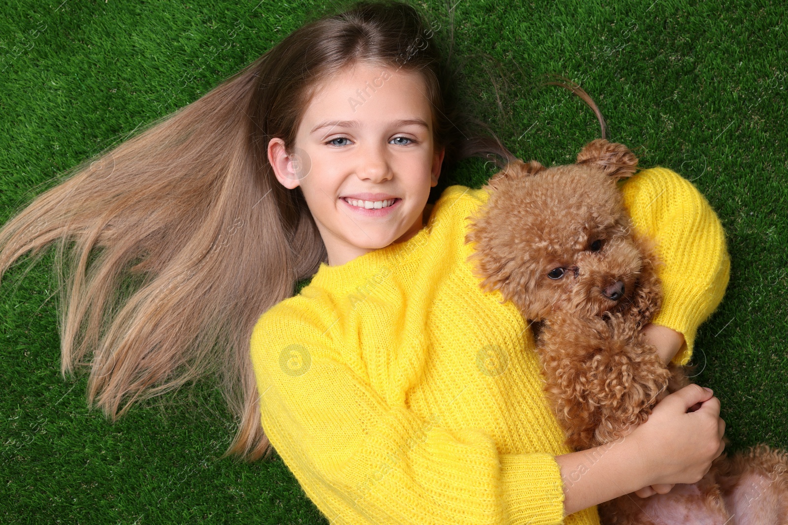 Photo of Little child with cute puppy on green grass, top view. Lovely pet