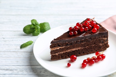 Plate with slice of chocolate cake and berries on wooden table. Space for text